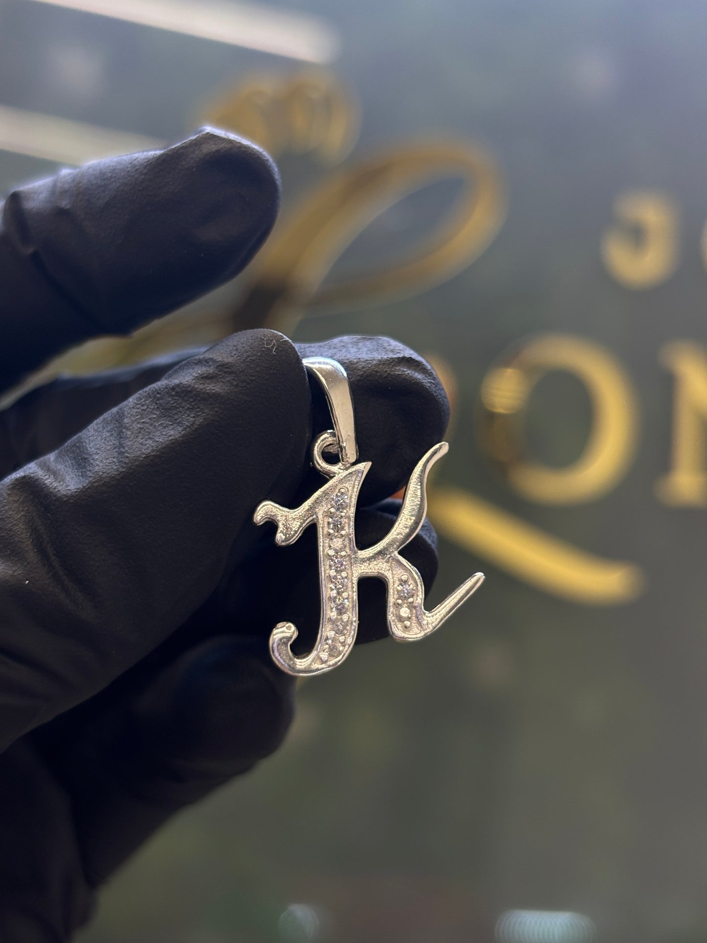 Inicial K cursiva plata
